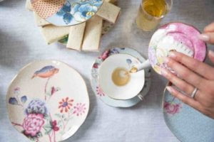 A person is pouring tea to cup to show the perfect way to host high tea at your own home
