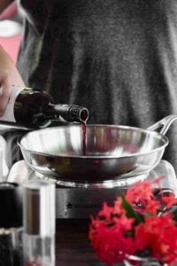 A person is pouring wine into a pan