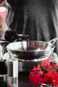 A person is pouring wine into a pan